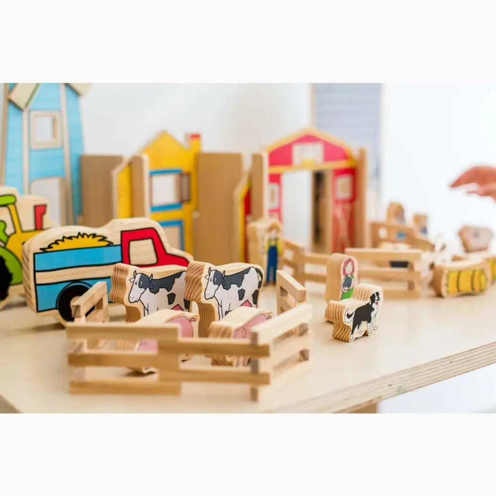 Wooden toy farm set with miniature animals, buildings, and vehicles.