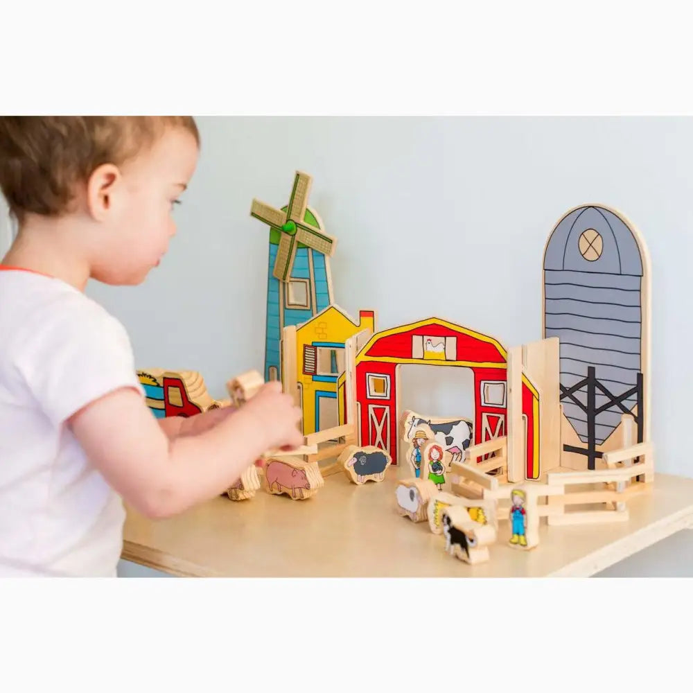 Wooden farm playset with barn, windmill, silo, and animal figures.