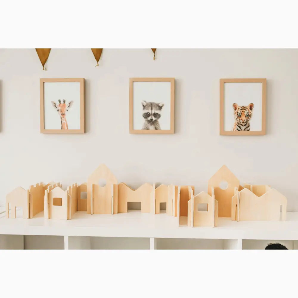 Wooden toy buildings or blocks arranged on a white surface.