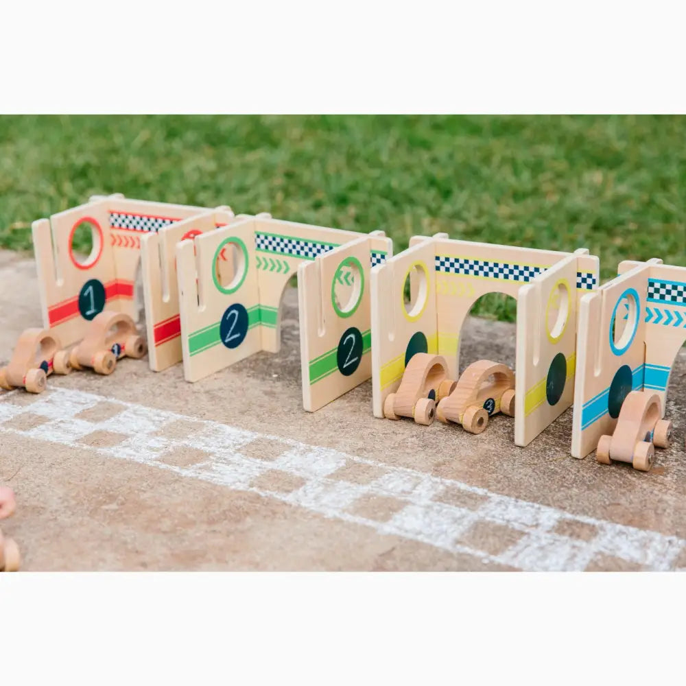 Wooden toy racing car set with numbered gates and small vehicles on a starting line.