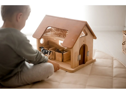 Wooden dollhouse or playhouse with a pitched roof and visible interior rooms.