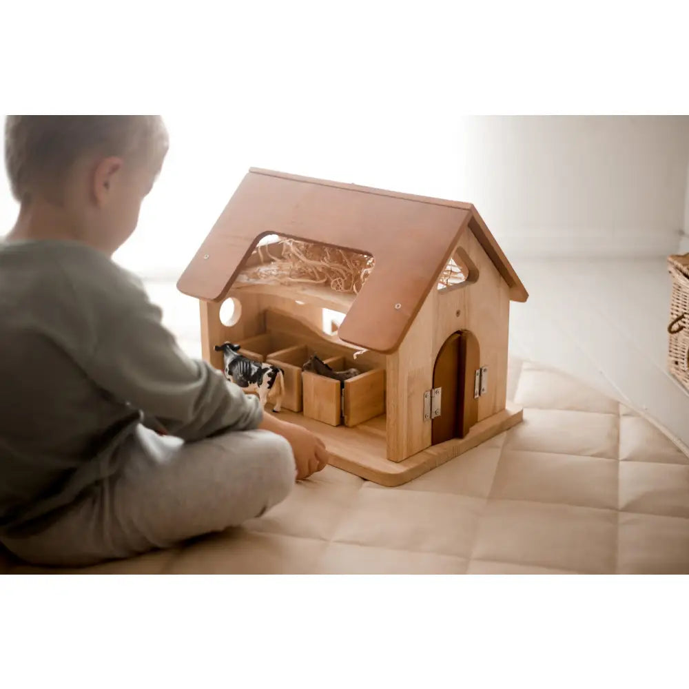 Wooden dollhouse or playhouse with a pitched roof and visible interior rooms.