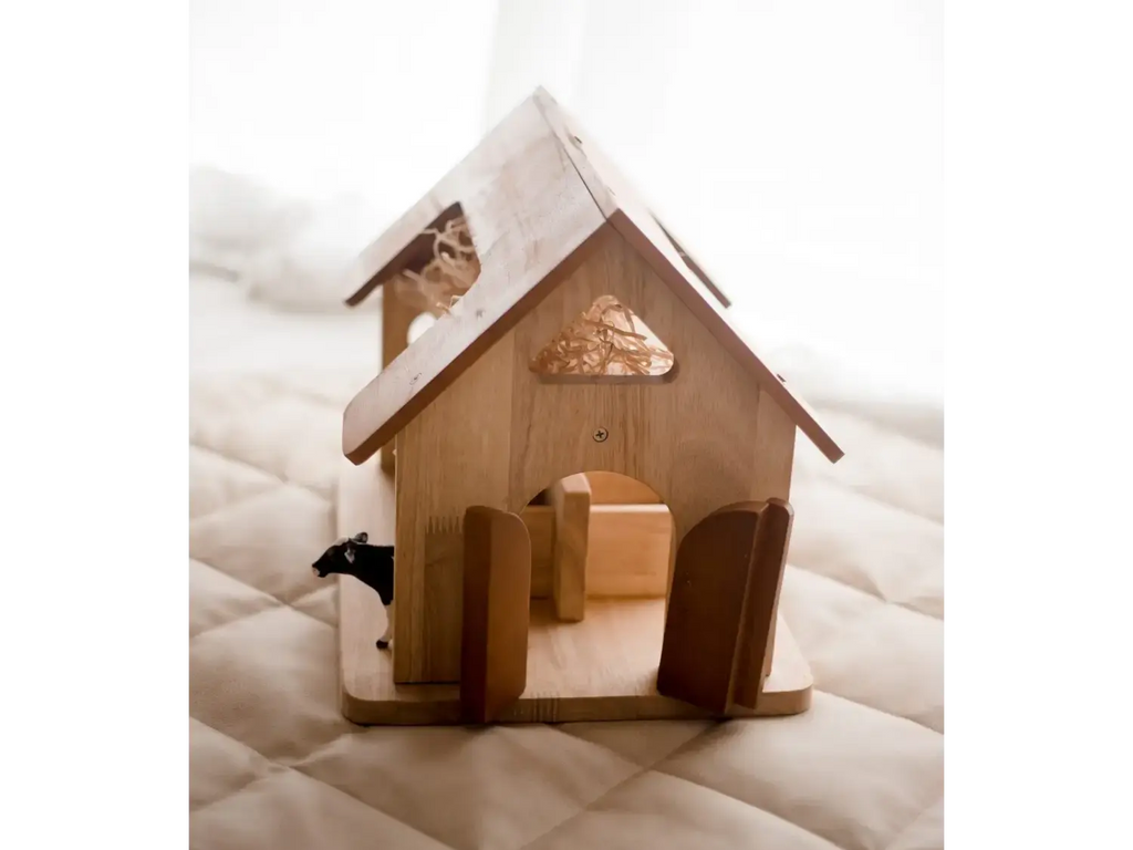Wooden dollhouse or miniature house with a peaked roof and open doorway.