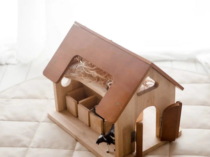 Wooden toy barn or stable with a pink roof and open doors.