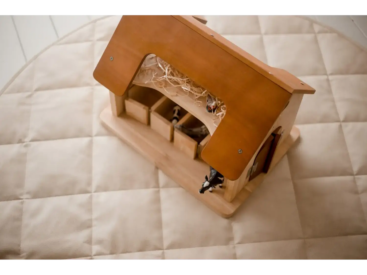 Wooden toy barn or stable with a peaked roof and openings.