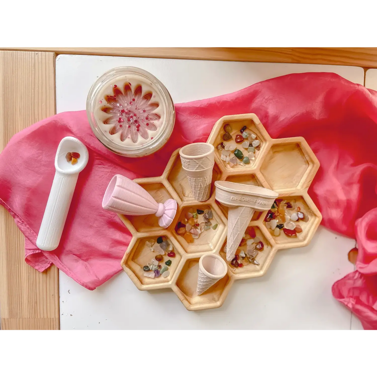 Hexagonal wooden tray with compartments containing colorful beads or small objects.