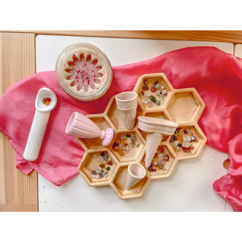 Hexagonal wooden tray with compartments containing colorful beads or small objects.