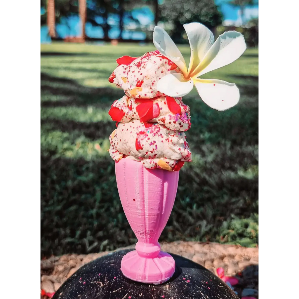 Ice cream sundae in a pink glass with a flower garnish.