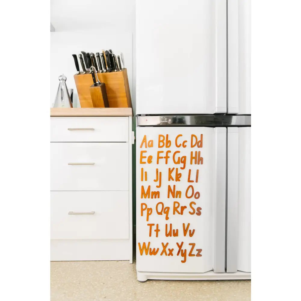 Refrigerator with colorful alphabet letters displayed on its door.