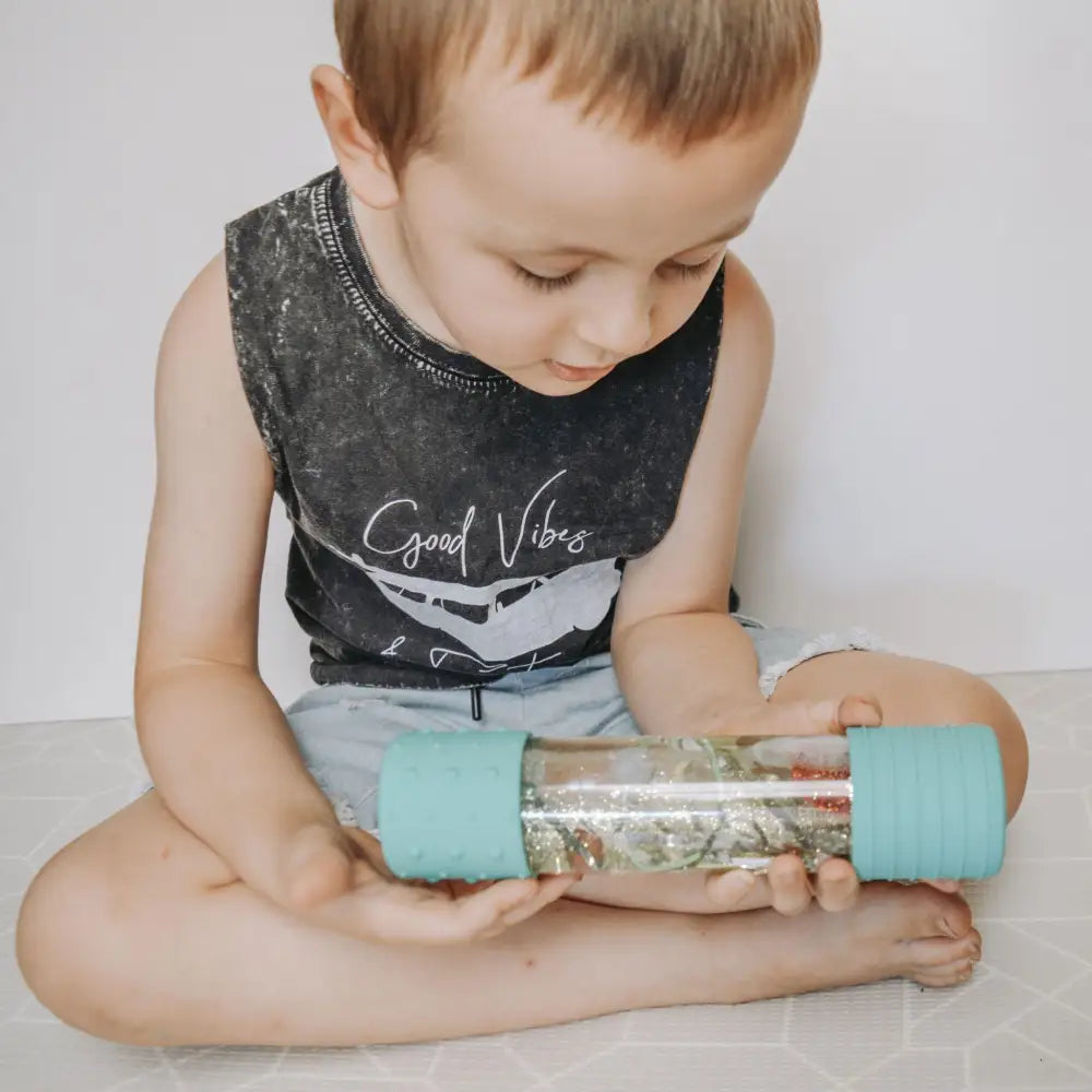 Child holding a sensory bottle filled with glitter and water.