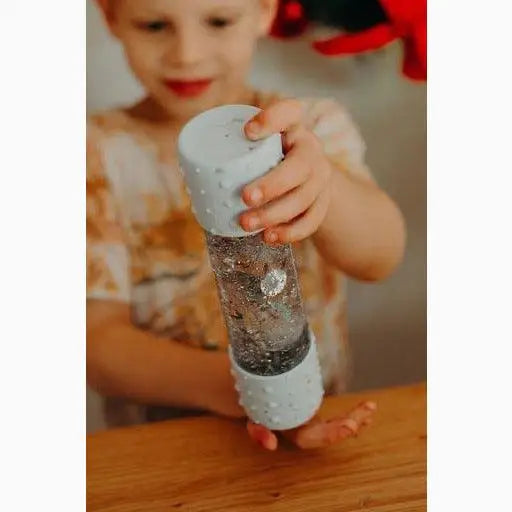 Glittery snow globe or sensory bottle being held by small hands.