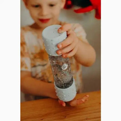 Glittery snow globe or sensory bottle being held by small hands.