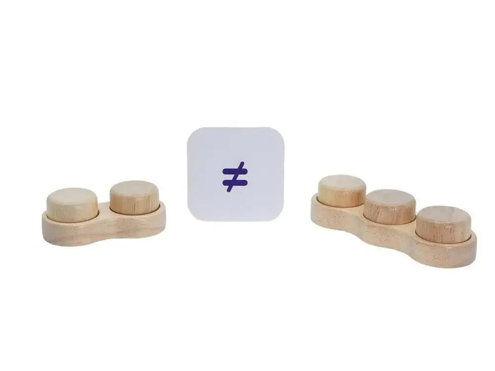 Mathematical inequality symbol ’not equal to’ on a white square card between two sets of wooden discs.