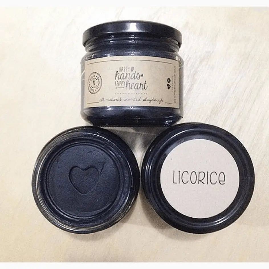Glass jar with a label reading ’handle with heart’ alongside two smaller jar lids, one embossed with a heart shape and the other labeled ’licorice’.