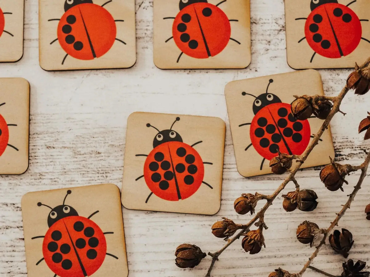 Wooden coasters decorated with bright red ladybug designs.