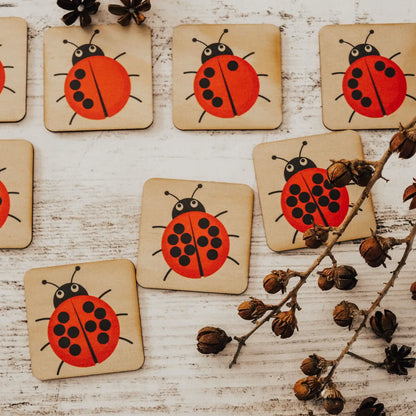 Wooden coasters decorated with bright red ladybug designs.