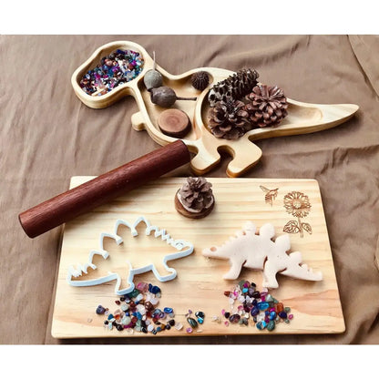 Wooden dinosaur-shaped craft board with compartments for beads and decorations.