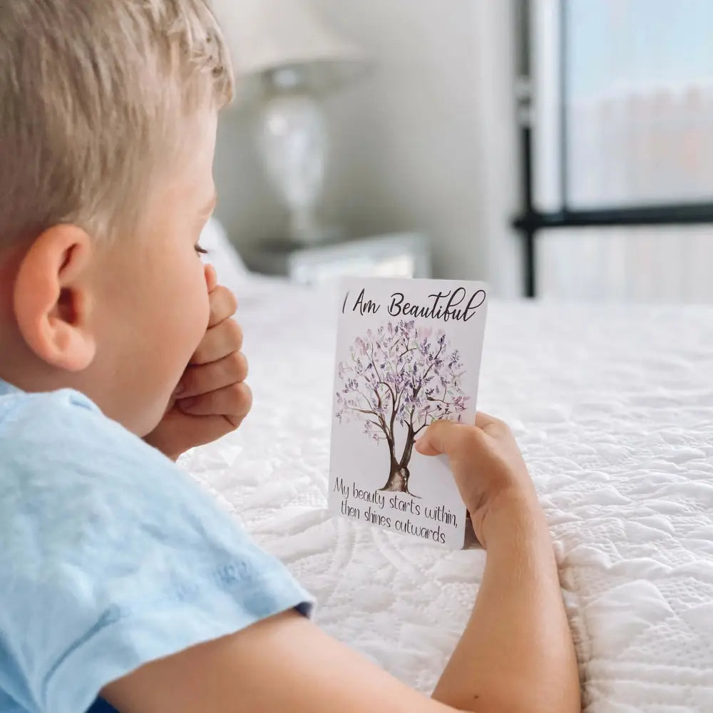 Card with a tree illustration and the text ’I Am Beautiful’ held by a child’s hands.