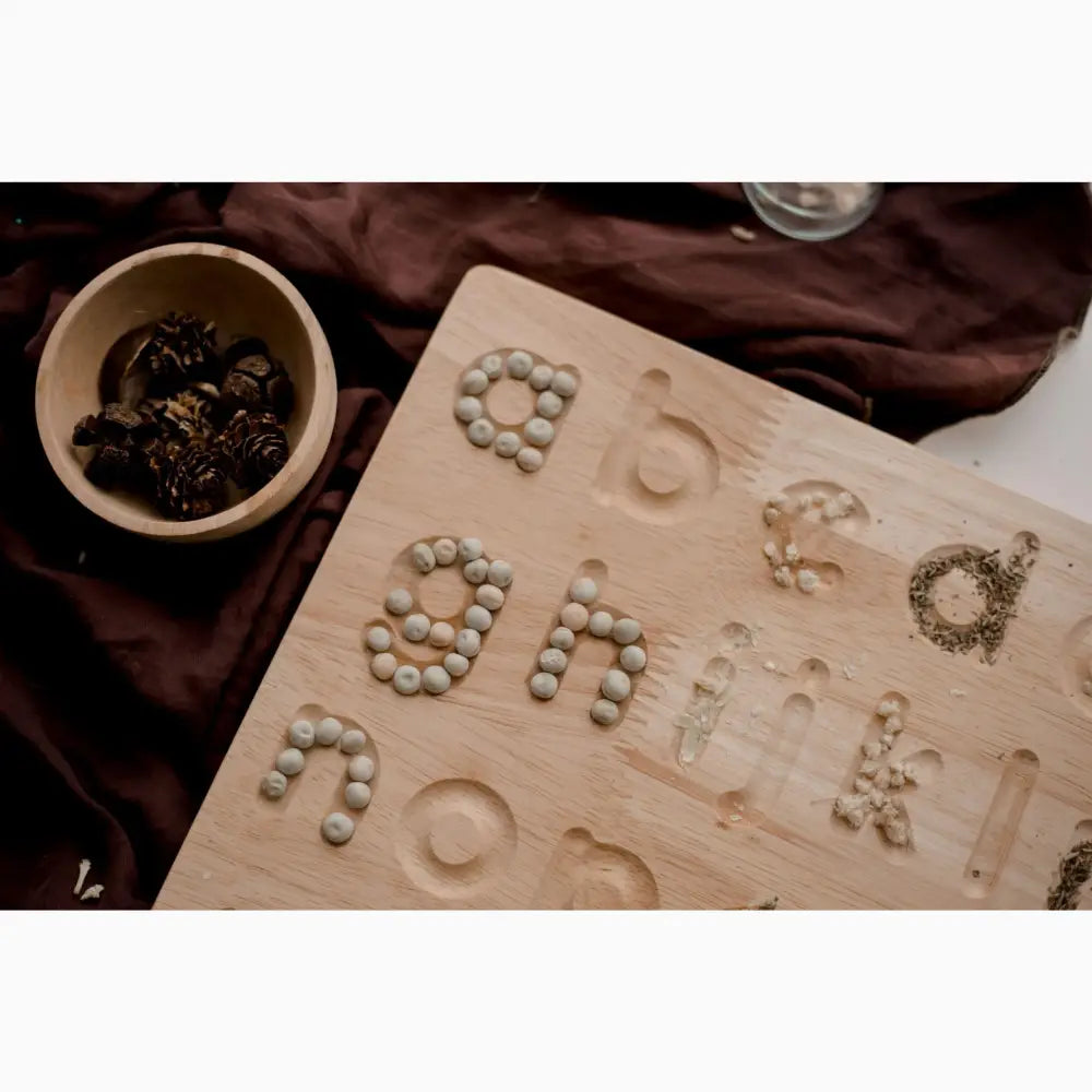 Wooden board with letters formed from small stones or pebbles.