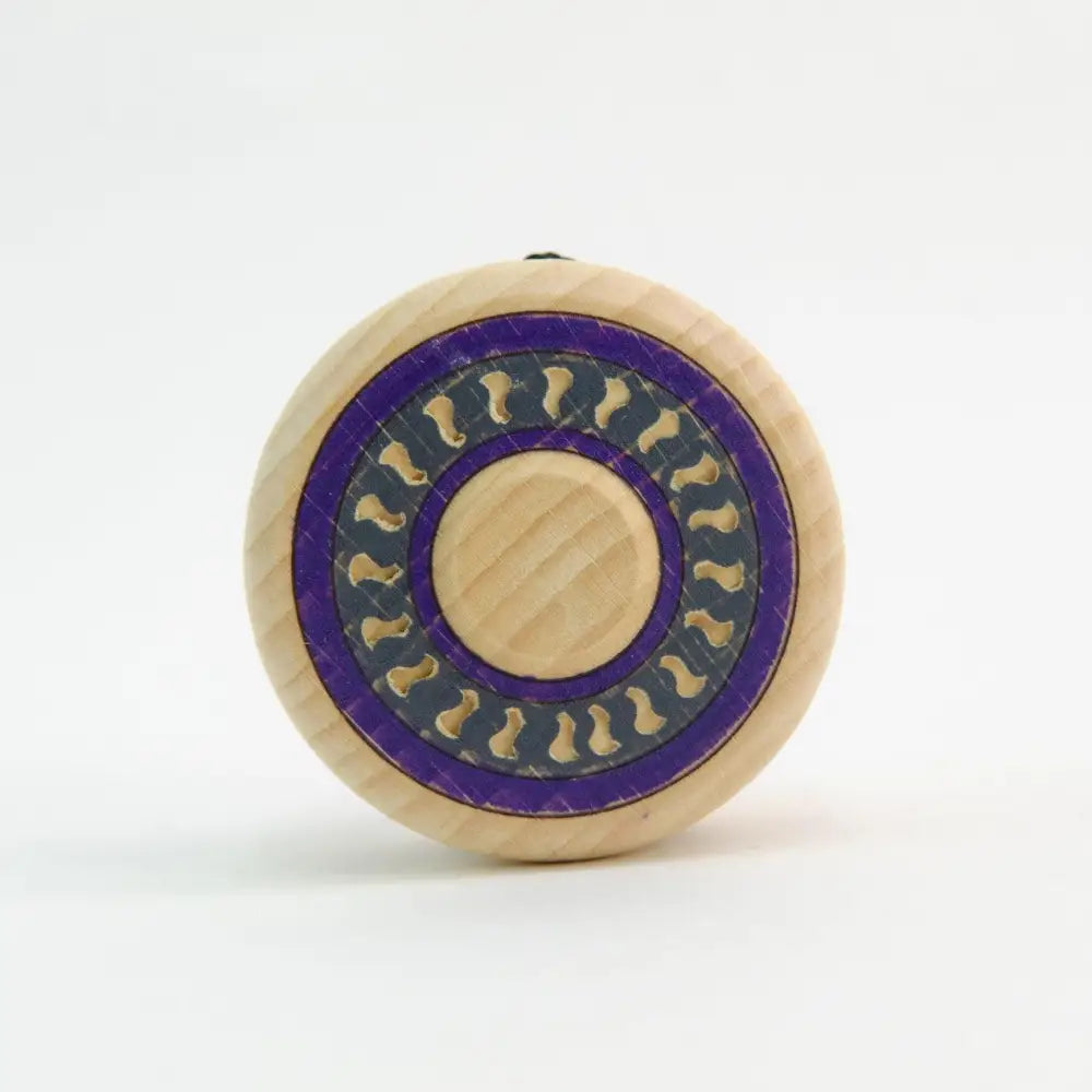 Circular wooden object with a purple and gold decorative pattern.