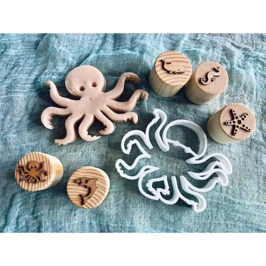 Wooden octopus-shaped cookie cutter alongside circular stamps with sea creature designs.