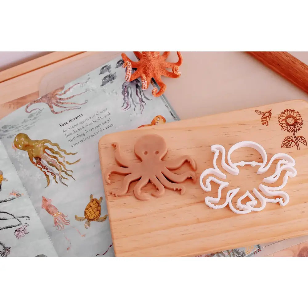 Wooden octopus-shaped cookie cutter on a cutting board.