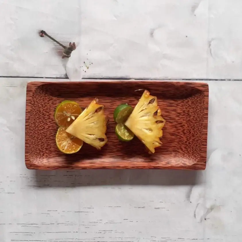 Rectangular wooden plate containing slices of pineapple and citrus fruit.