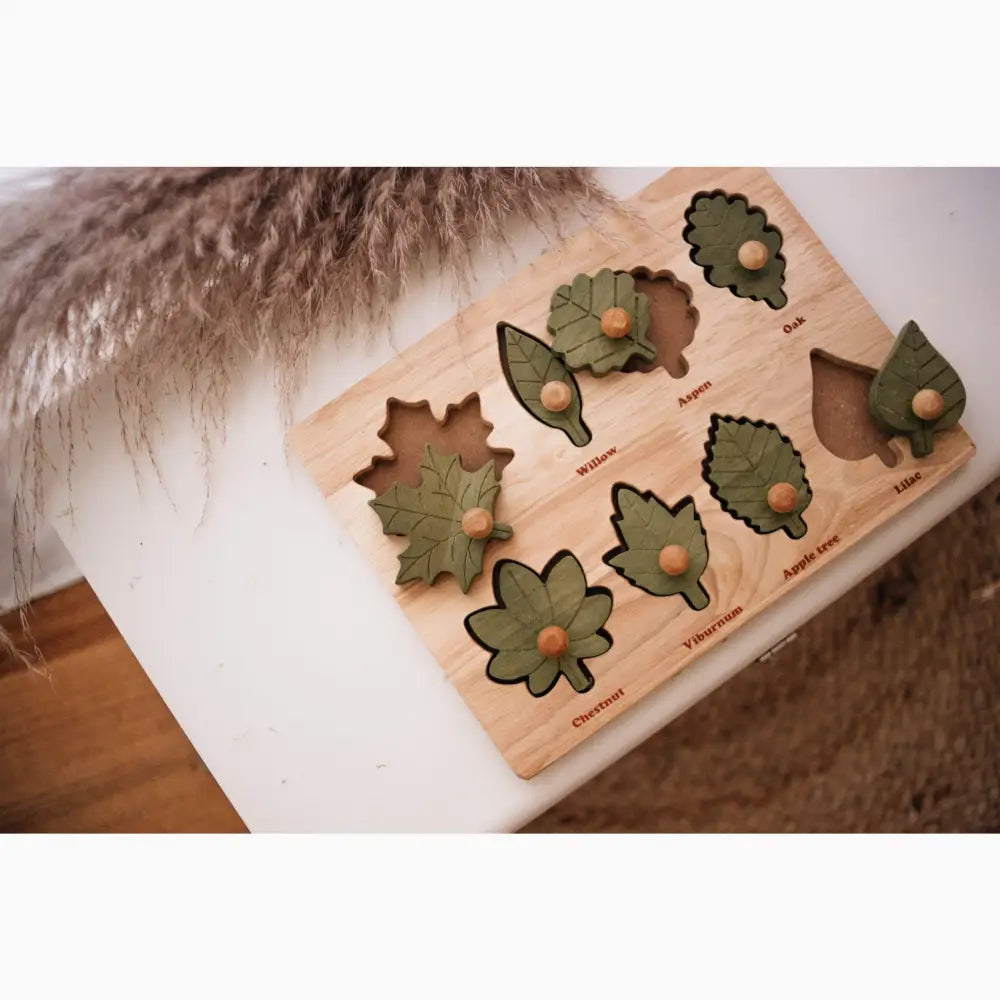 Wooden puzzle board with leaf-shaped cutouts and pieces.