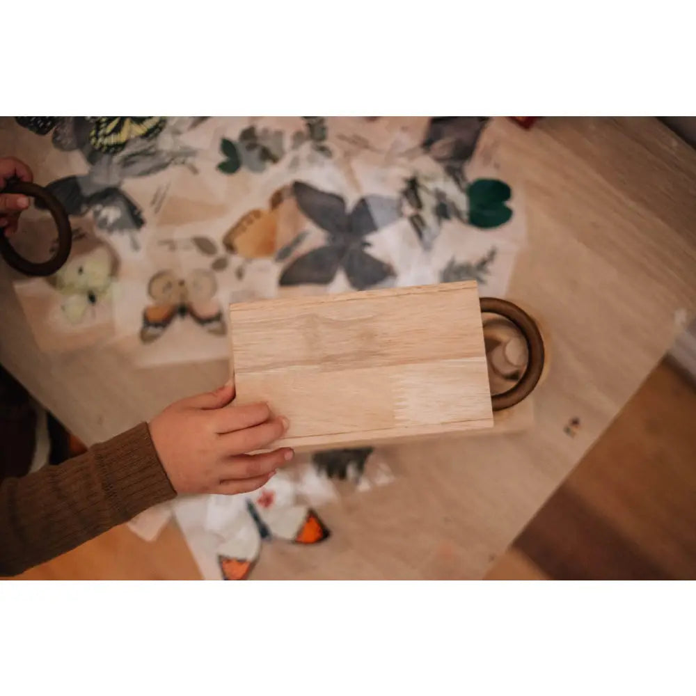 Wooden cutting board or serving plank held by a hand.