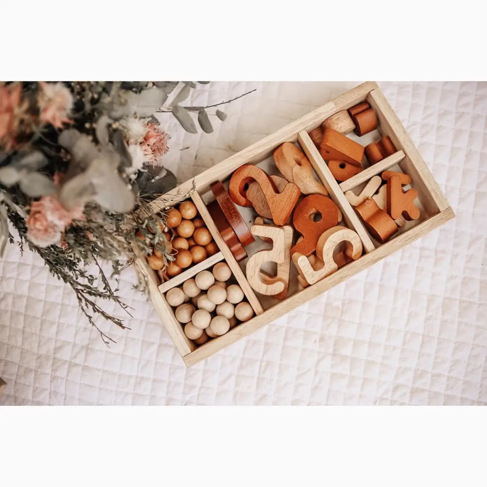 Wooden compartmentalized tray containing various wooden toys and beads.