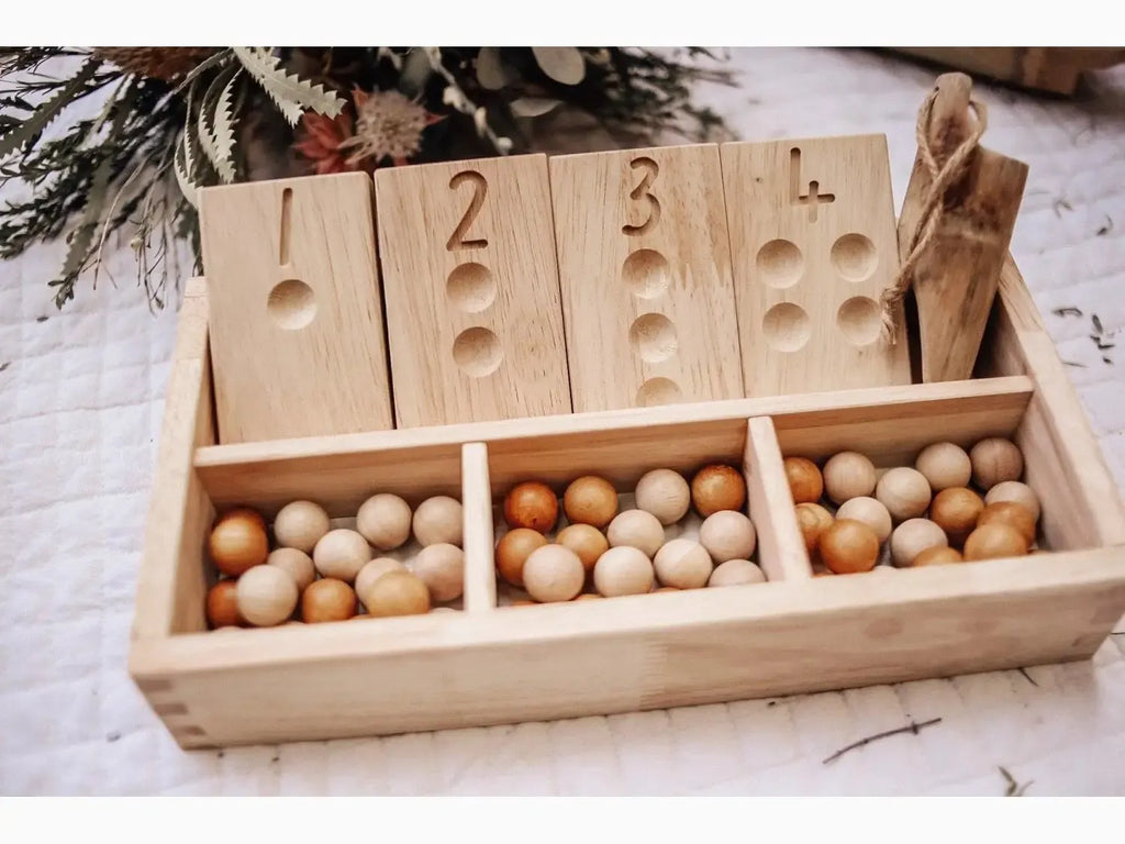 Wooden counting tray with numbered compartments and small eggs.