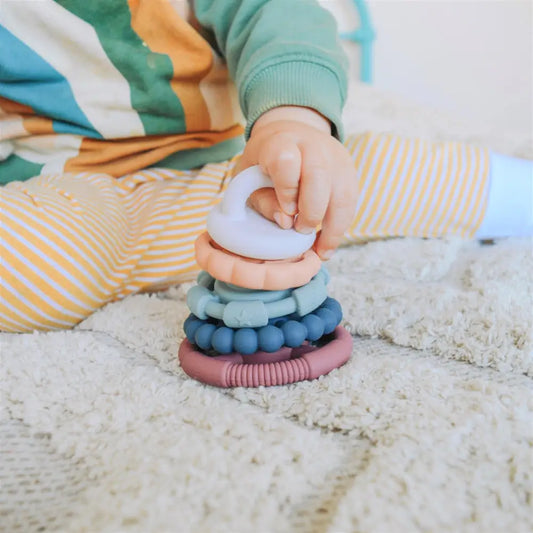 Colorful stacking toy with various textured rings being held by a small hand.