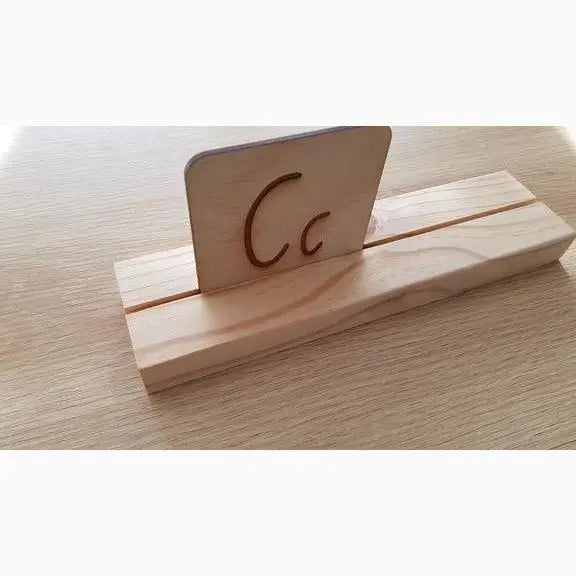 Wooden stand holding a card with the lowercase letter ’c’ written on it.