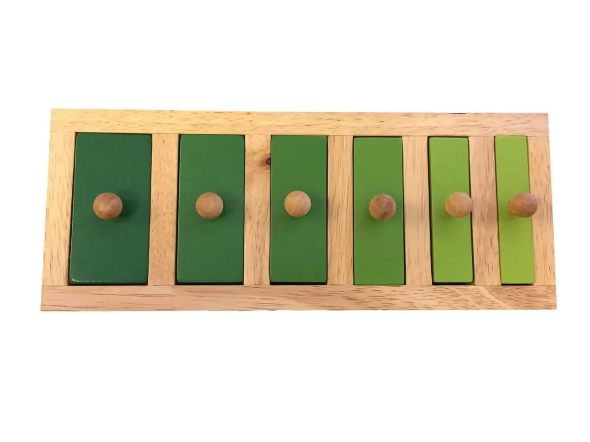Wooden educational toy with six green rectangular panels of varying sizes and knobs.