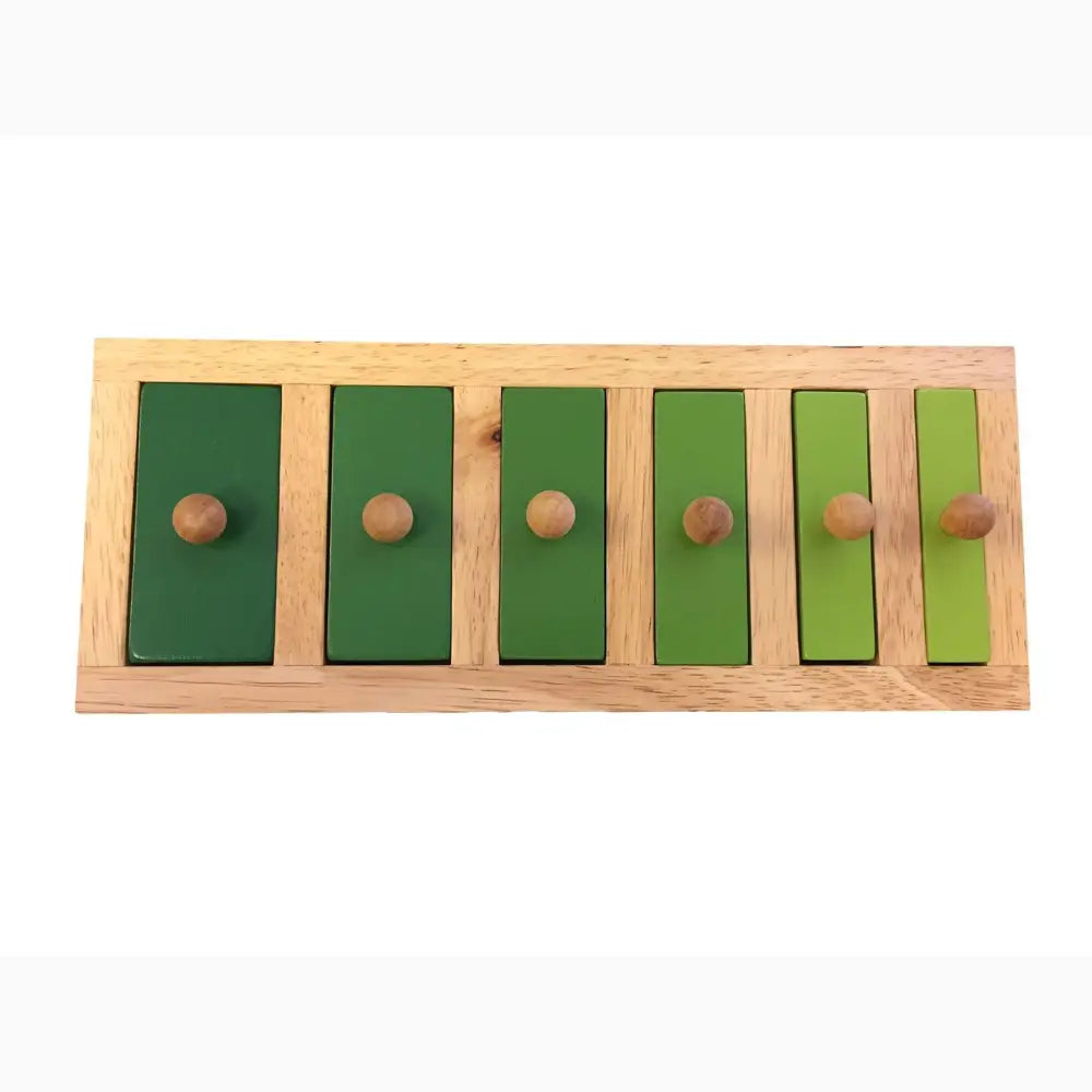 Wooden educational toy with six green rectangular panels of varying sizes and knobs.