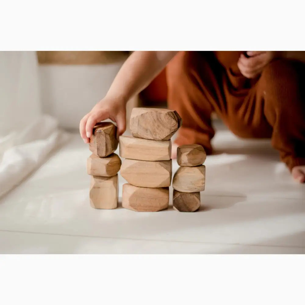 Stacked wooden blocks or toys arranged in three columns on a white surface.