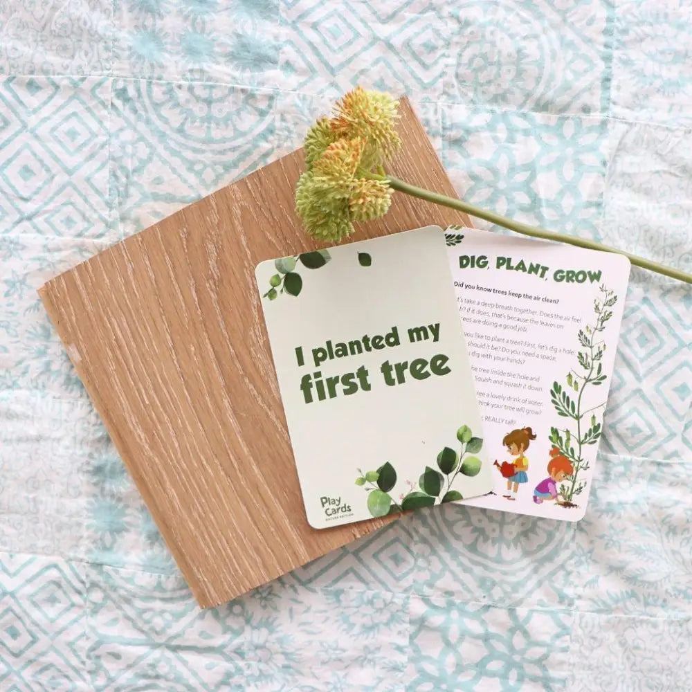 A card stating ’I planted my first tree’ alongside a wooden plank and a small plant stem.