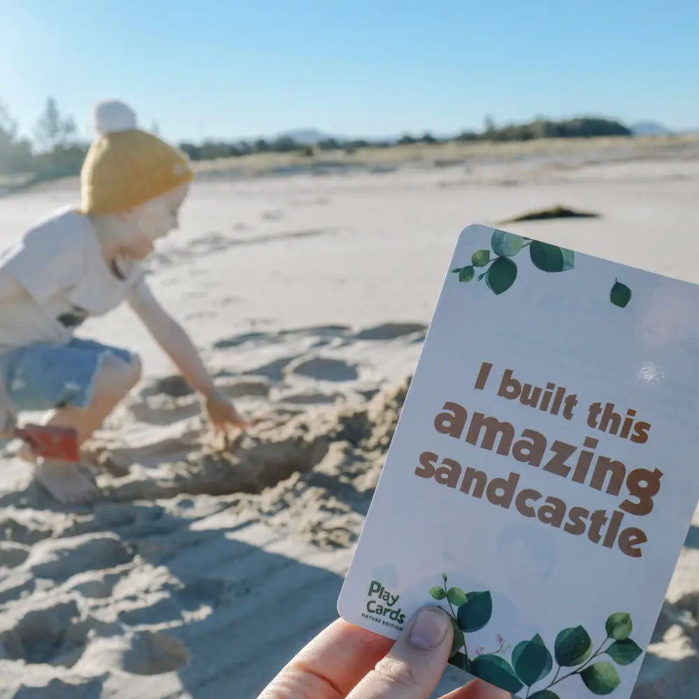 Card held in a hand with text reading ’I built this amazing sandcastle’.