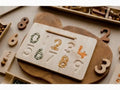 Wooden board with number-shaped indentations filled with various materials.
