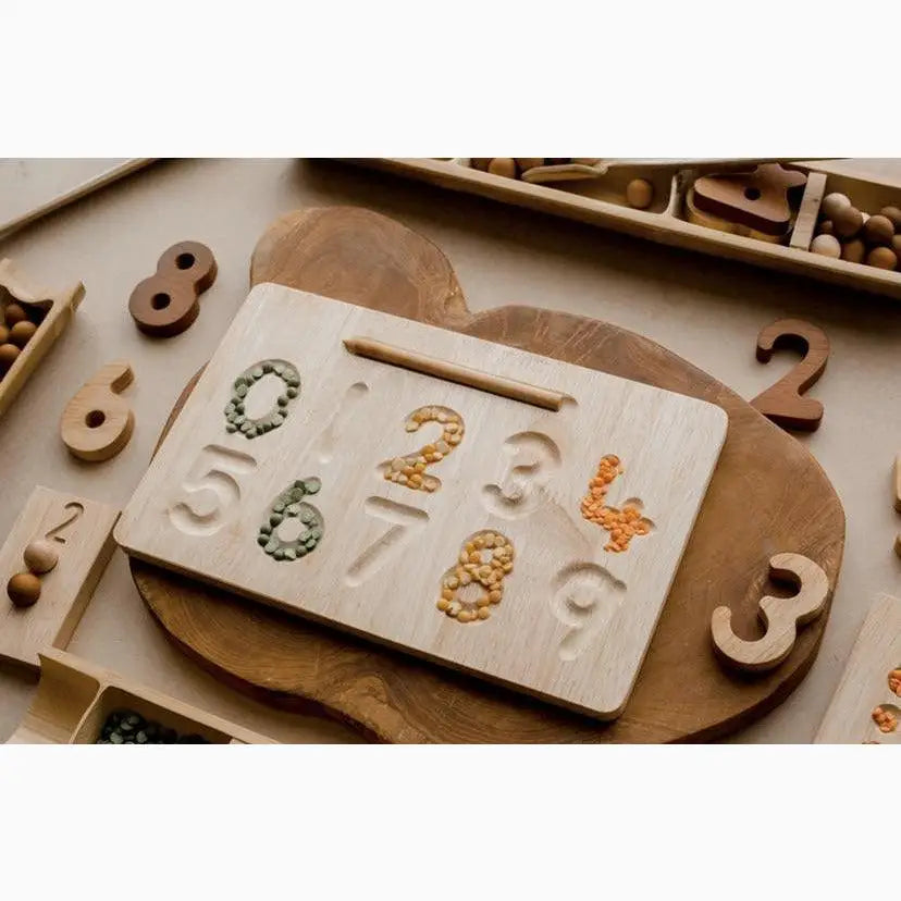 Wooden board with number-shaped indentations filled with various materials.