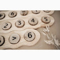 Wooden number board with circular number tiles and a decorative sprig of dried flowers.