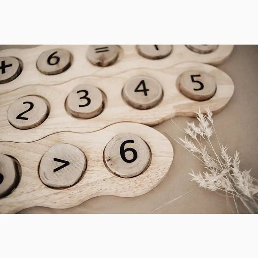 Wooden number board with circular number tiles and a decorative sprig of dried flowers.