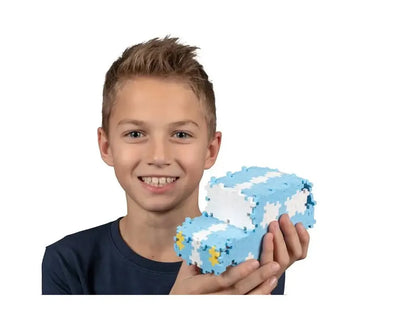 Smiling young person holding a light blue and white pixelated object shaped like the number 8.