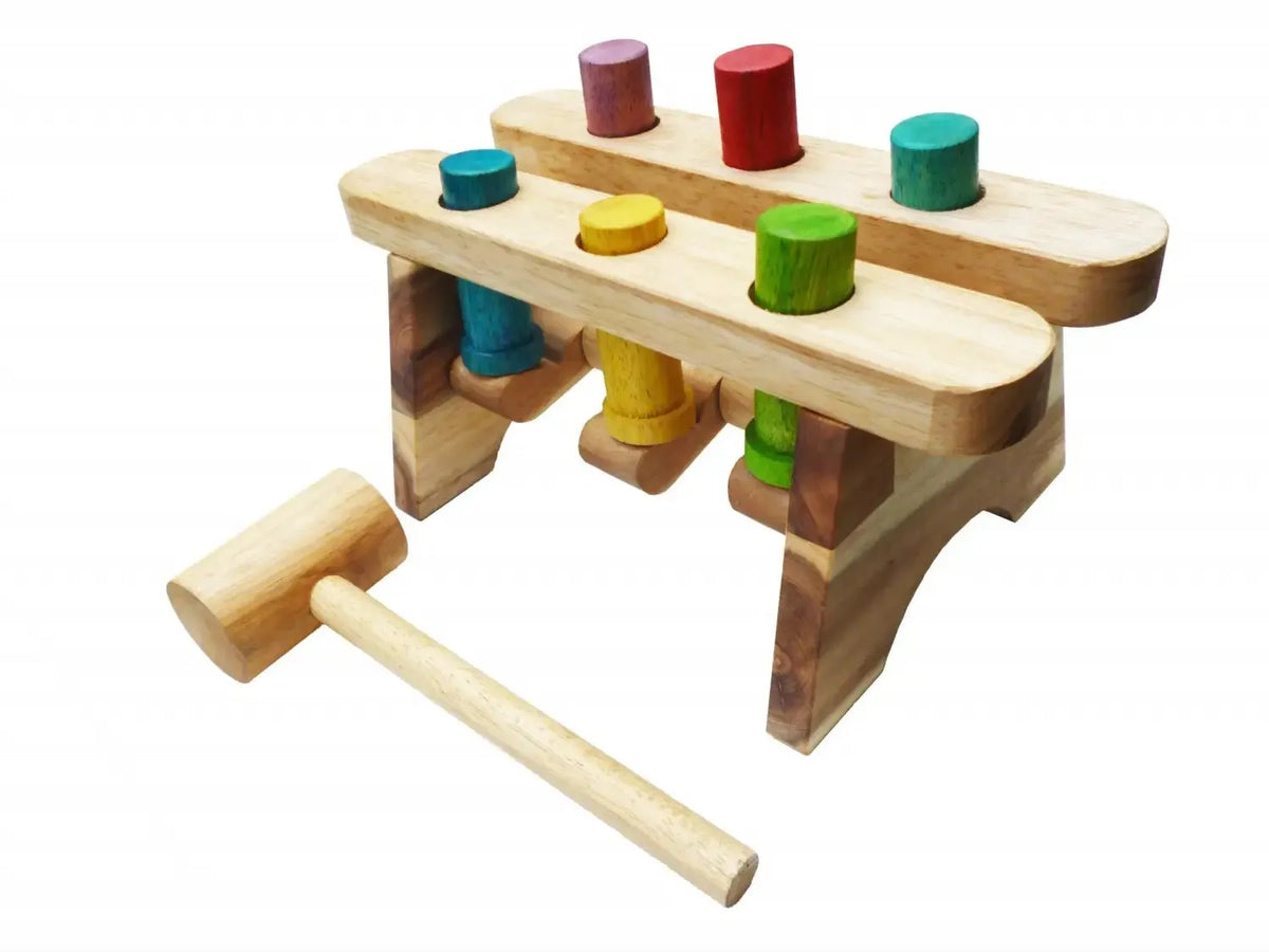 Wooden toy pounding bench with colorful cylindrical pegs and a hammer.