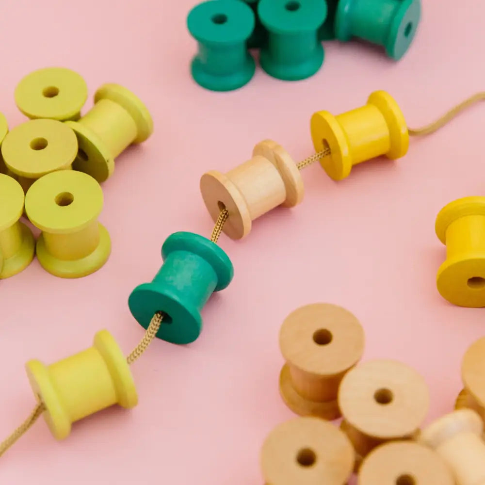 Colorful wooden spools or bobbins scattered on a surface.