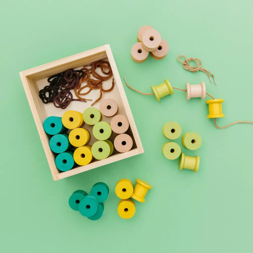 Wooden box containing colorful wooden spools and hair elastics.