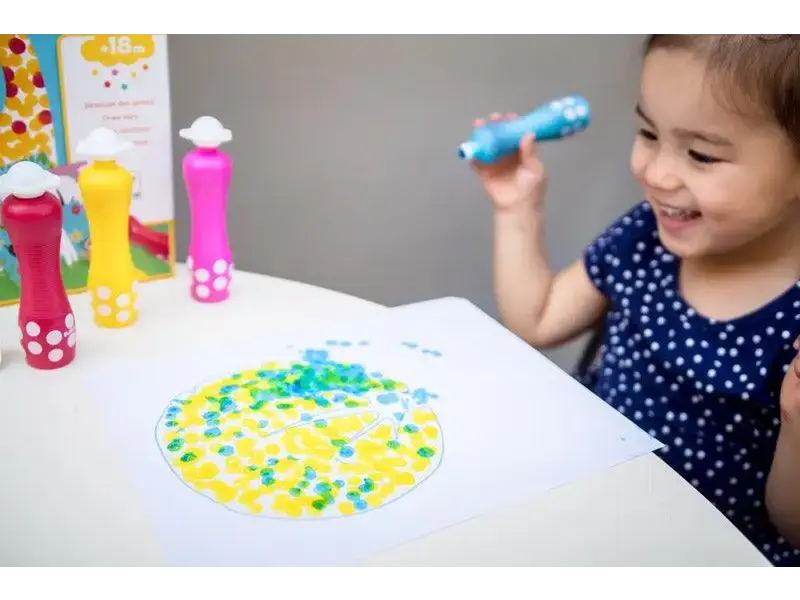 Child playing with colorful dot markers on paper.
