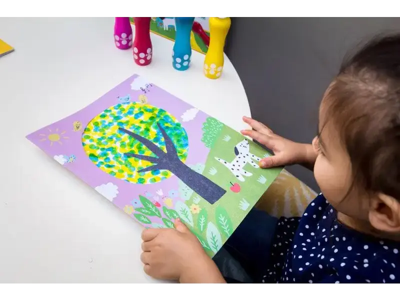 Colorful tree artwork being created by a child using paper mosaic technique.