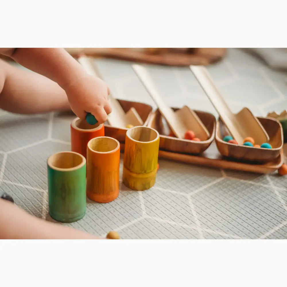 Colorful wooden cups or containers arranged alongside small wooden trays or bowls.