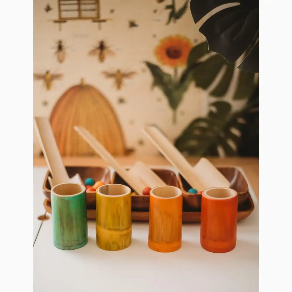 Four colorful ceramic cups with spoons arranged in a row.